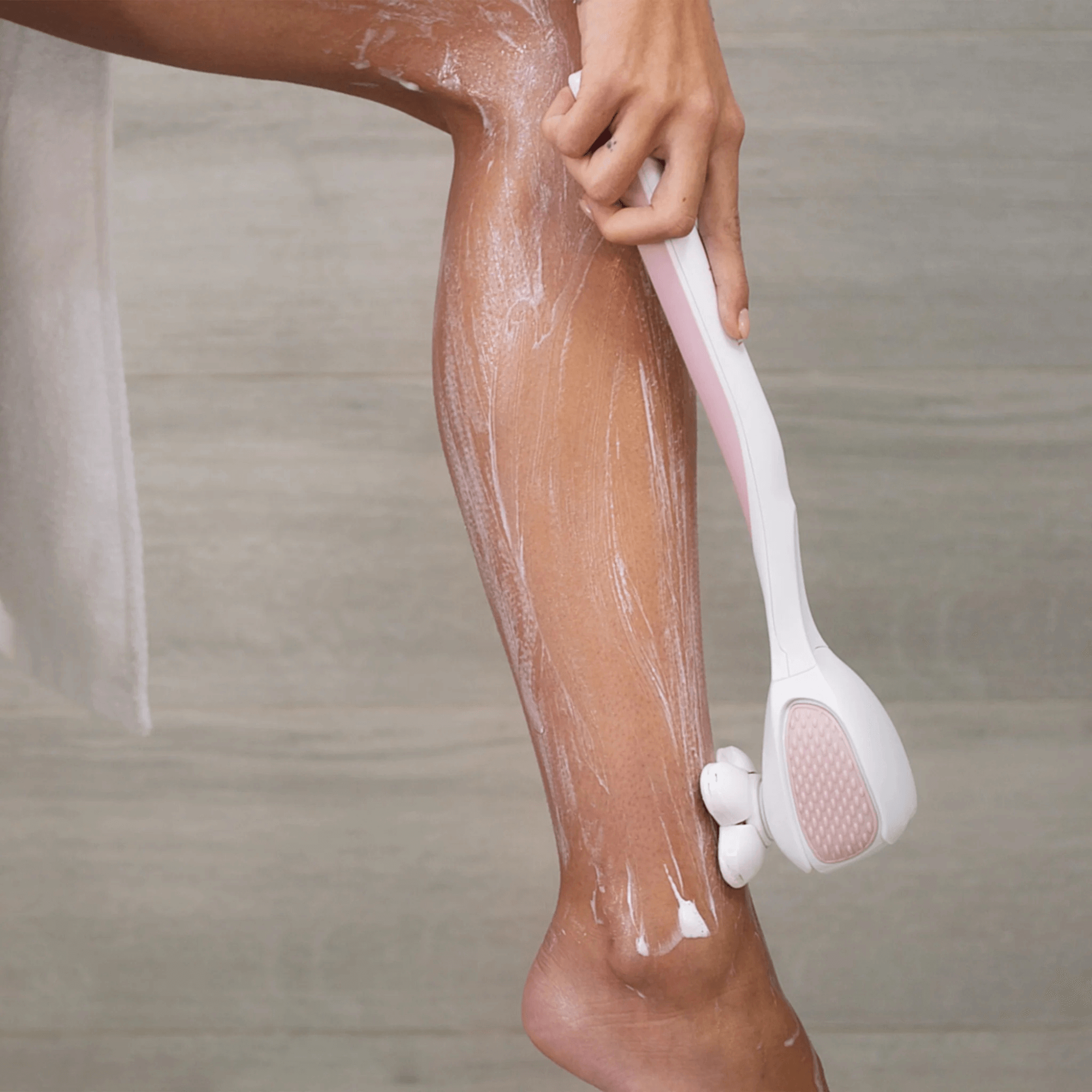 PosheEra waterproof electric shaver being used for a wet shave in the shower. Extended ergonomic handle provides effortless leg shaving with smooth, irritation-free results.